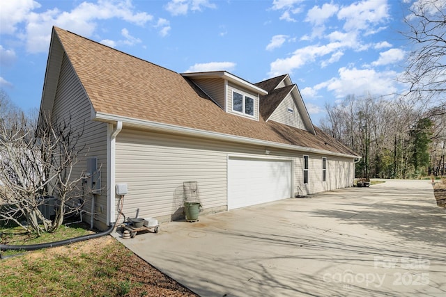 view of side of property with driveway and roof with shingles