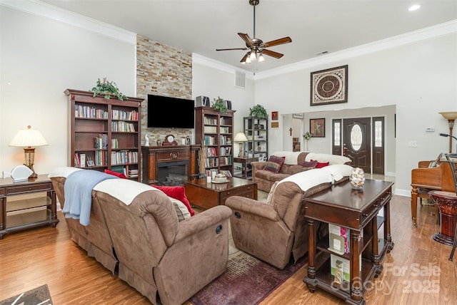 living area with ornamental molding, visible vents, a fireplace, and wood finished floors