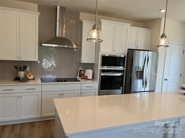 kitchen featuring stainless steel appliances, wall chimney exhaust hood, backsplash, and white cabinetry