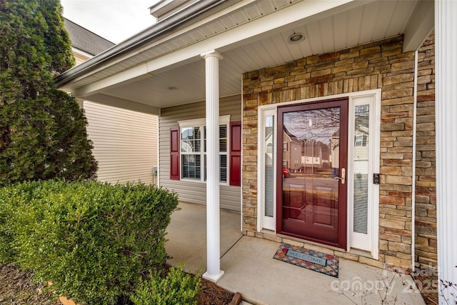 entrance to property featuring a porch and brick siding