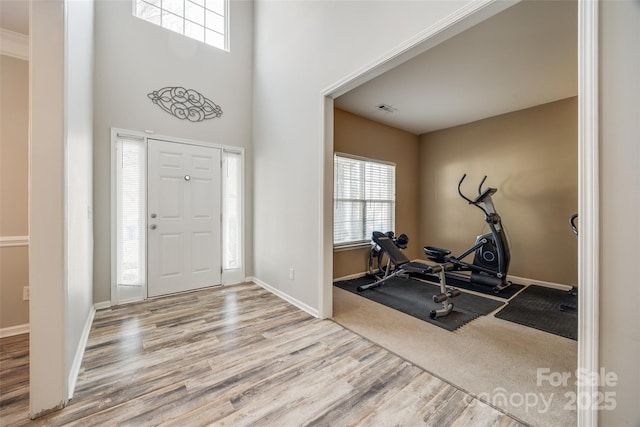 entrance foyer with a high ceiling, wood finished floors, visible vents, and baseboards