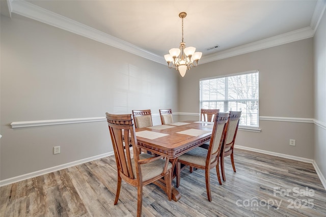 dining room with baseboards, visible vents, a chandelier, and wood finished floors