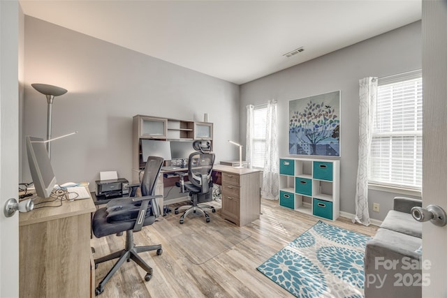 office space featuring baseboards, light wood finished floors, and a healthy amount of sunlight