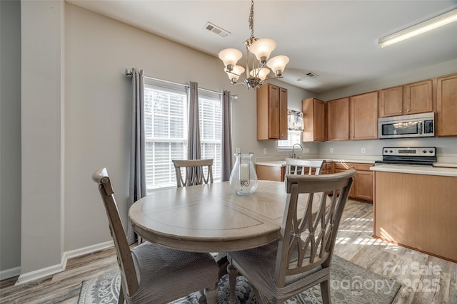 dining room with baseboards, light wood-type flooring, visible vents, and a notable chandelier