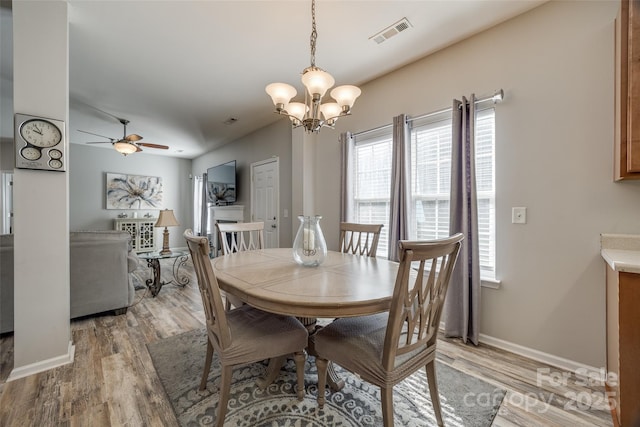 dining space with light wood-style floors, visible vents, baseboards, and ceiling fan with notable chandelier