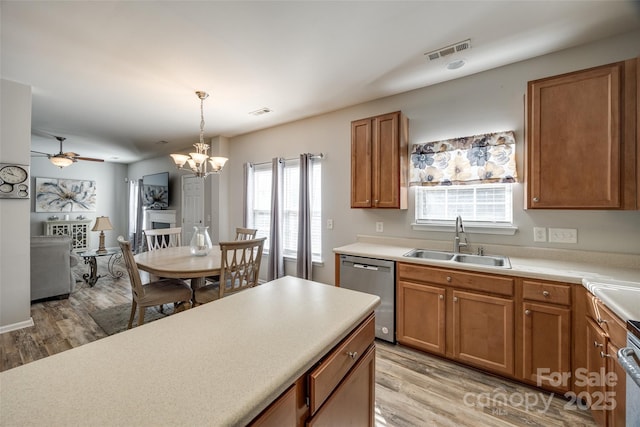 kitchen with visible vents, stainless steel dishwasher, light wood-style floors, brown cabinetry, and a sink