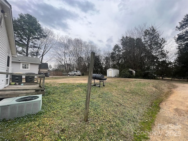 view of yard with a deck, central AC, a storage unit, and an outbuilding