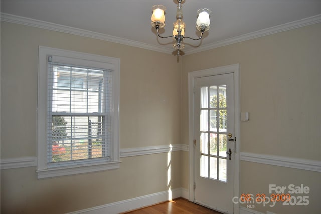 doorway to outside with crown molding, a wealth of natural light, and a notable chandelier