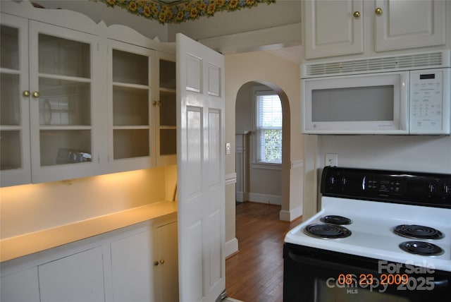 kitchen featuring electric range, white microwave, arched walkways, and glass insert cabinets