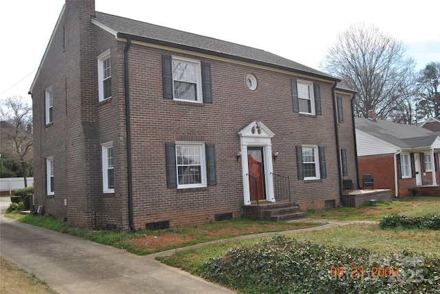 colonial home with brick siding and a chimney