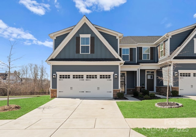 craftsman-style house featuring board and batten siding, a front yard, driveway, and a garage