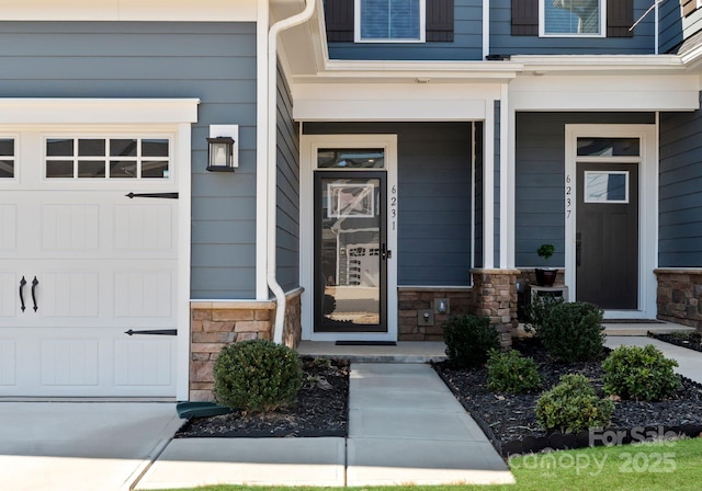 view of exterior entry with stone siding and an attached garage