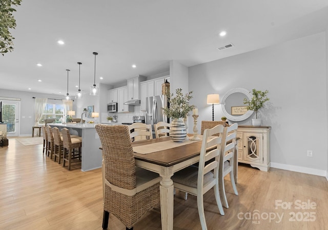 dining space featuring baseboards, light wood finished floors, visible vents, and recessed lighting