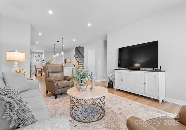 living area featuring light wood-style floors, stairs, baseboards, and recessed lighting