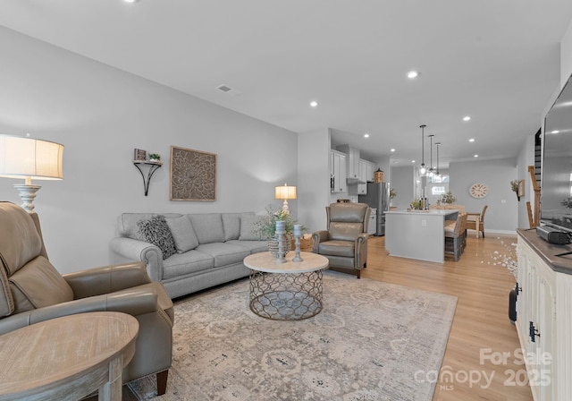 living room featuring light wood-style floors, visible vents, and recessed lighting