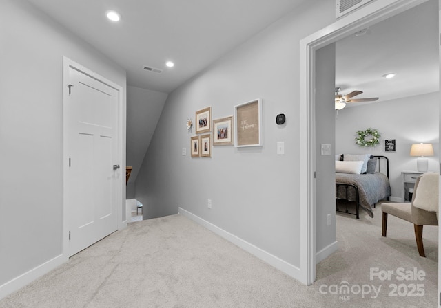 hallway with carpet floors, recessed lighting, visible vents, and an upstairs landing