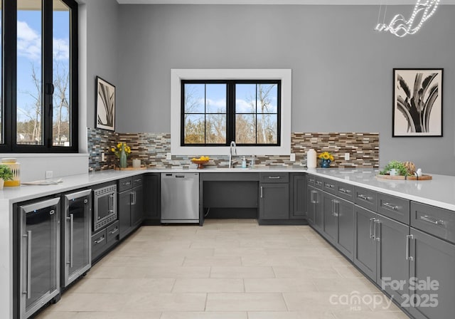 kitchen with stainless steel appliances, wine cooler, a sink, and light countertops