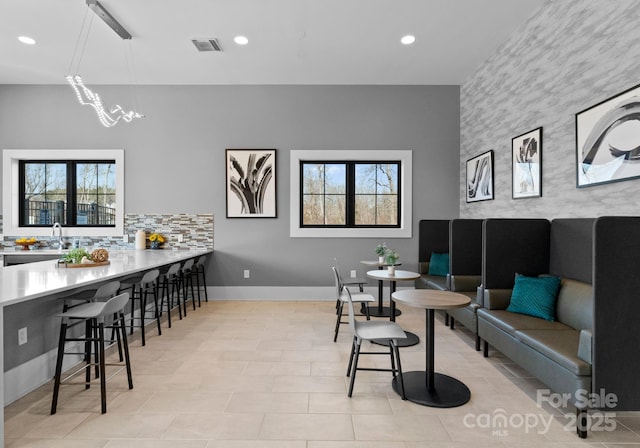 dining space with baseboards, an accent wall, visible vents, and recessed lighting