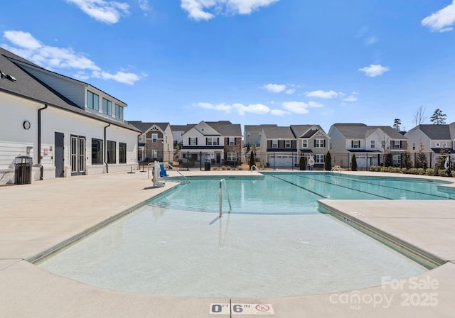 pool with a patio area, fence, and a residential view