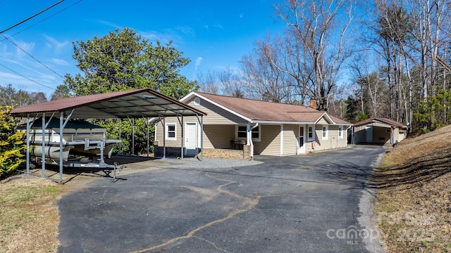 ranch-style house featuring aphalt driveway, a chimney, and a detached carport