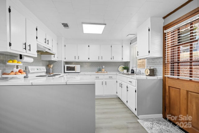 kitchen with white appliances, visible vents, under cabinet range hood, and white cabinets