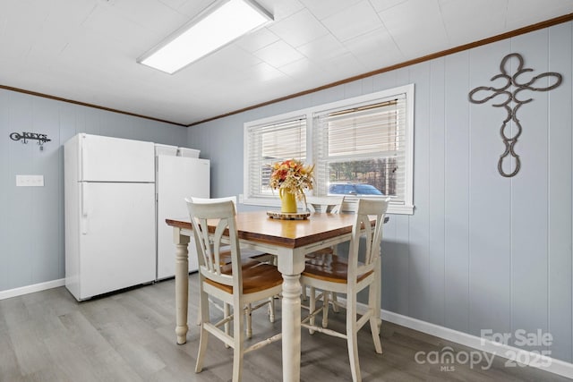 dining space with light wood-style floors, baseboards, and ornamental molding