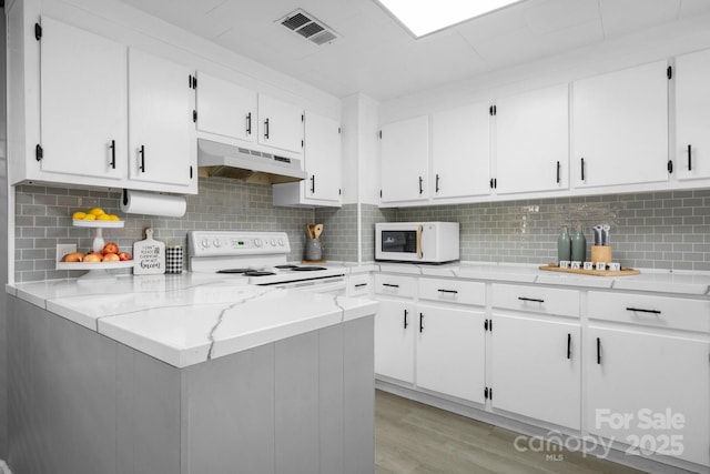 kitchen with light wood finished floors, visible vents, white cabinets, white appliances, and under cabinet range hood