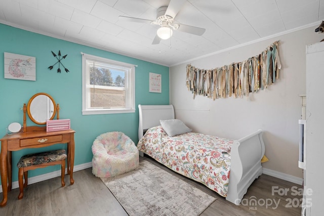 bedroom with baseboards, ceiling fan, wood finished floors, and crown molding