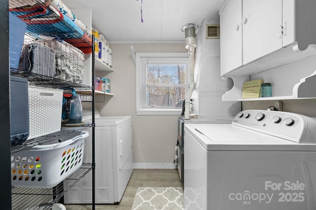 laundry room with light wood-style flooring, washer and clothes dryer, cabinet space, and visible vents