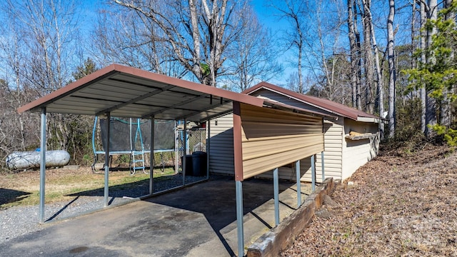 exterior space featuring driveway, a trampoline, and a carport