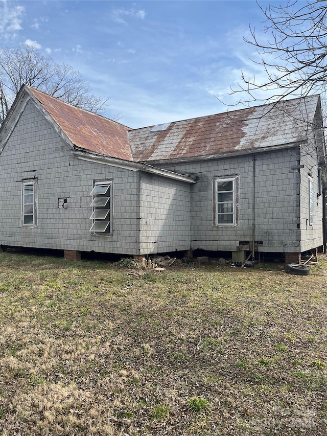 view of side of property with a shingled roof and a lawn