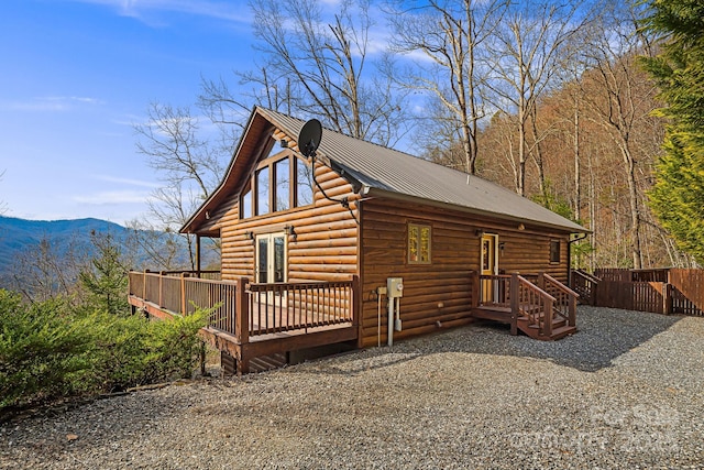 view of front facade featuring a deck with mountain view, metal roof, and fence