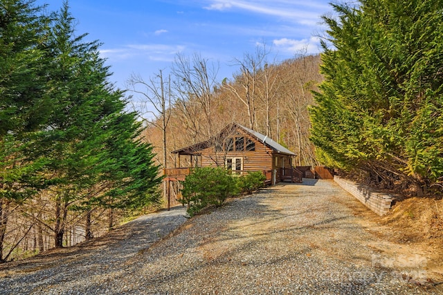 view of front of home featuring driveway and a wooded view