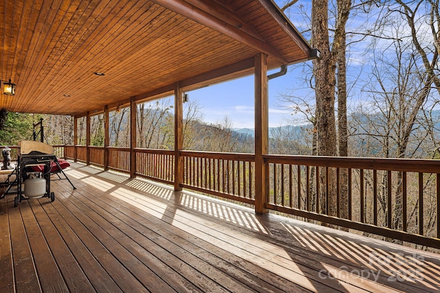 wooden terrace featuring a mountain view and a view of trees