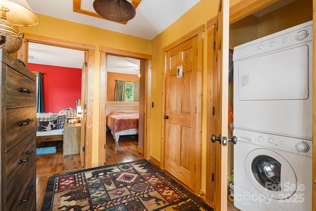 clothes washing area with stacked washer / drying machine and wood finished floors