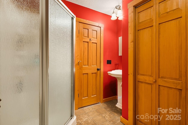 full bath featuring a shower stall and baseboards