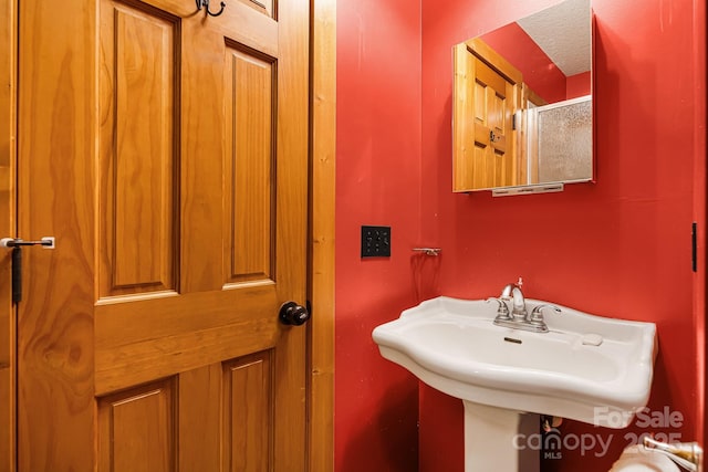 bathroom with an enclosed shower and a sink