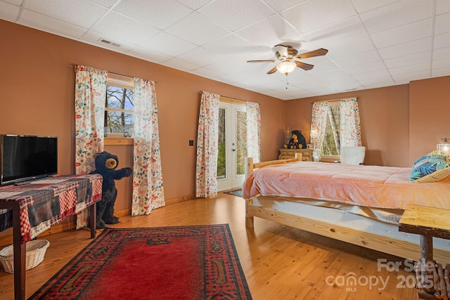 bedroom featuring ceiling fan, a drop ceiling, wood finished floors, and visible vents