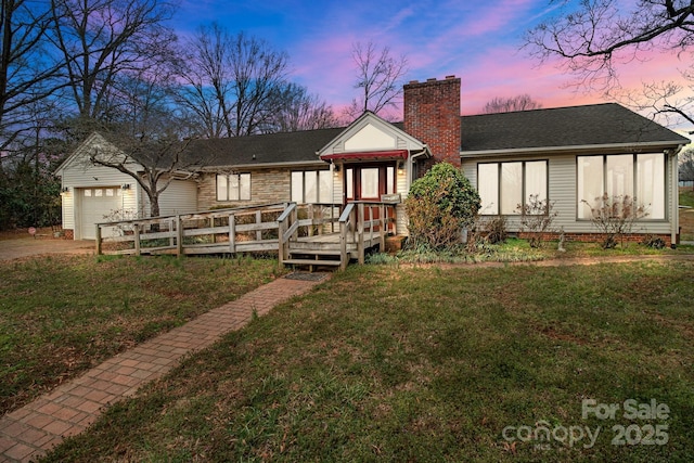 view of front facade with concrete driveway, a chimney, roof with shingles, an attached garage, and a front yard