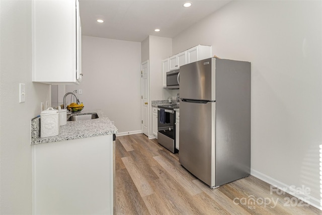 kitchen featuring baseboards, white cabinets, light wood-style flooring, stainless steel appliances, and a sink