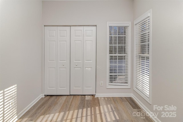 unfurnished bedroom featuring a closet, wood finished floors, and baseboards