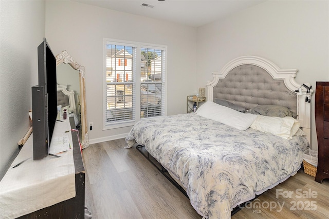 bedroom featuring wood finished floors, visible vents, and baseboards