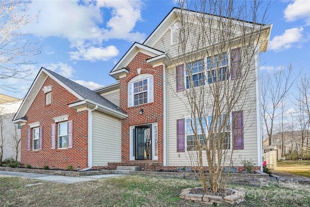 traditional-style house featuring a front yard and brick siding