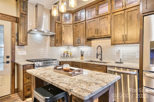 kitchen with brown cabinets, tasteful backsplash, a sink, dishwasher, and wall chimney exhaust hood