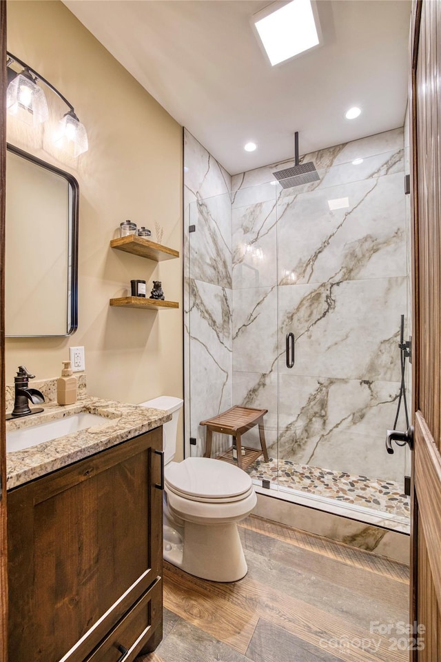 full bath featuring toilet, recessed lighting, wood finished floors, vanity, and a marble finish shower