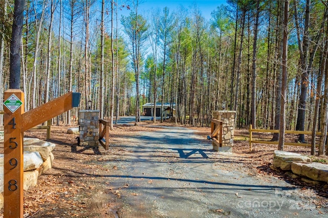 view of road with driveway and a wooded view