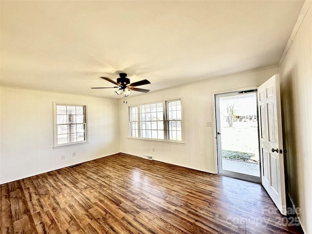 unfurnished room with a wealth of natural light, dark wood-style flooring, and ceiling fan