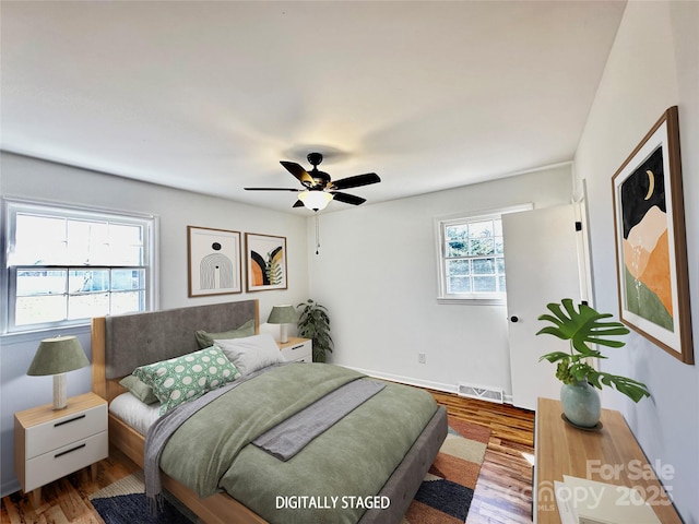 bedroom with ceiling fan, visible vents, and wood finished floors