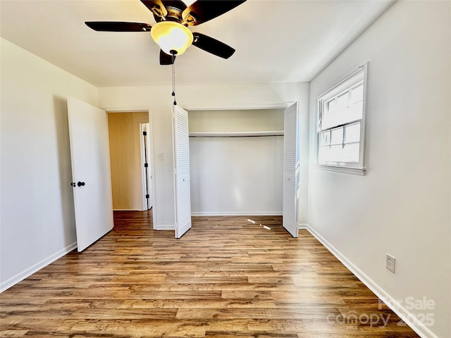 unfurnished bedroom with a closet, ceiling fan, baseboards, and wood finished floors