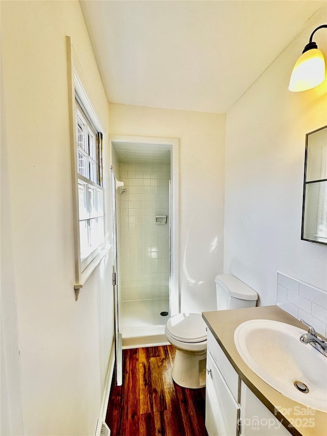 bathroom with toilet, a stall shower, wood finished floors, and vanity